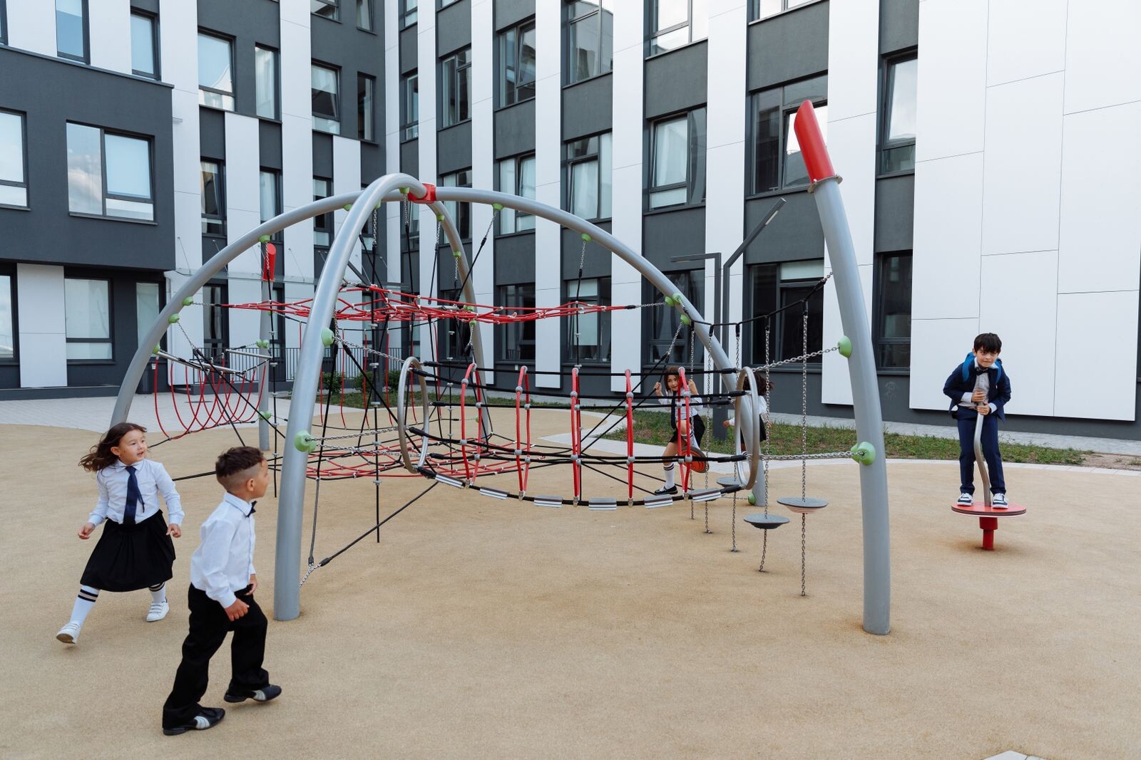 Children enjoy playtime in a modern school playground with climbing equipment.